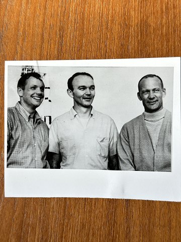 NASA: Small original black and white photograph of the three Apollo 11 astronauts Neil Armstrong, Mike Collins and Edwin Aldrin, gelatin silver, July 1969 with the Apollo V rocket in the background