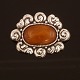 A large amber mounted silver brooch. Stamped by Thorvald Bindesbøll and Holger Kyster, Denmark. Size: 6,5x5cm