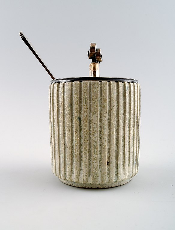 Arne Bang and Georg Jensen: Jam Jar in stoneware modeled with vertically fluted pattern. Decorated with light gray glaze.With lid and jam spoon in sterling silver.