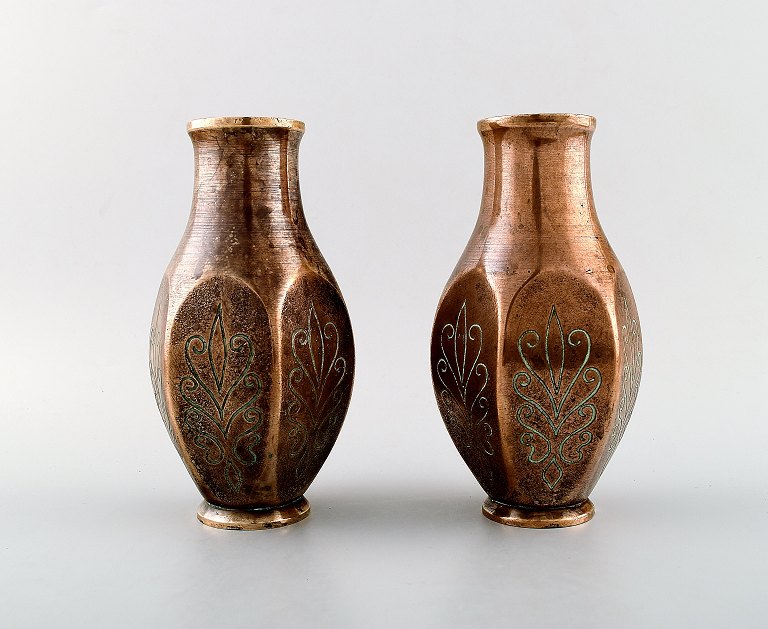 A pair of art deco Tinos Bronze vases in massive patinated bronze molded with foliage.