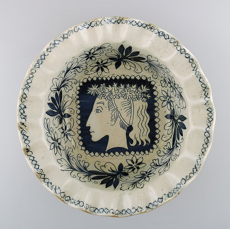 Unika Birger Kaipiainen (1915–1988) for Arabia, finsk keramiker.
Skål dekoreret i blå nuancer med kvinde i profil.