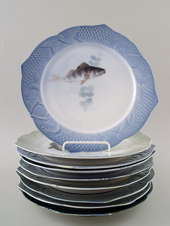 Arnold Krog for Royal Copenhagen : "Fiskestel" af porcelæn, Ni tallerkener dekoreret i farver med forskellige fisk.