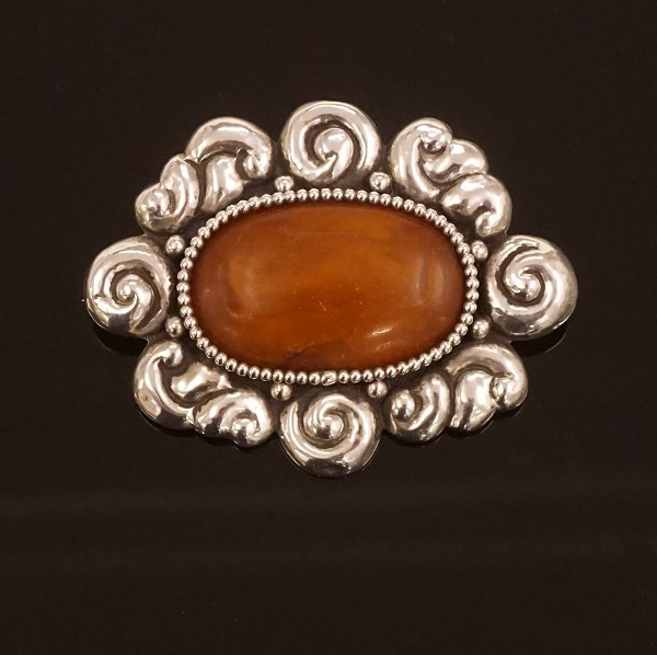 A large amber mounted silver brooch. Stamped by Thorvald Bindesbøll and Holger Kyster, Denmark. Size: 6,5x5cm
