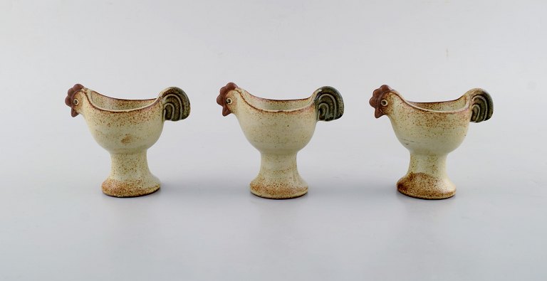 Lisa Larson for Gustavsberg. Three glazed ceramic egg cups from the "Easter" series designed as hens. Dated 1982.