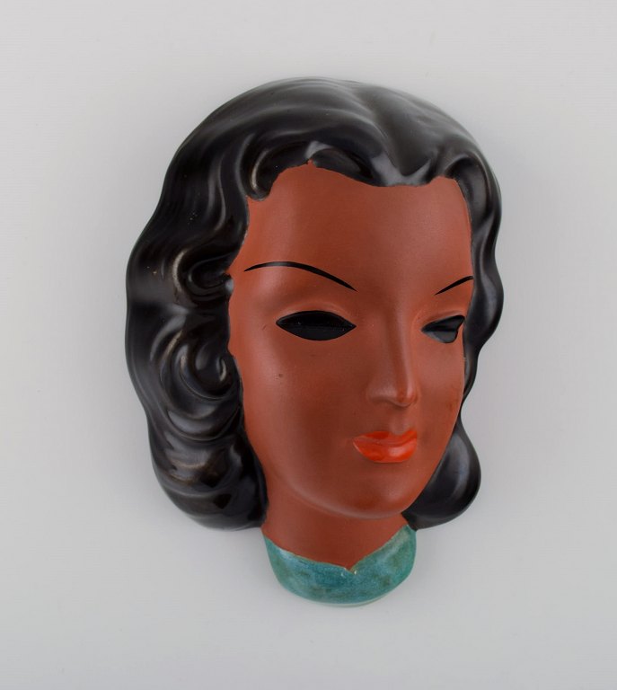 Goldscheider, Austria. Art deco female face in handpainted glazed ceramics. Dated 1953.