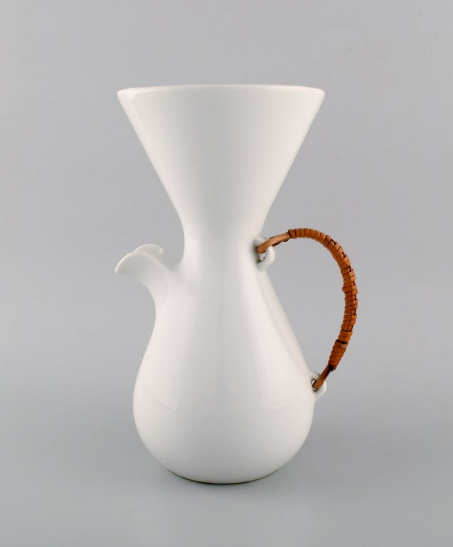 Freeman Lederman. Large modernist jug in white glazed ceramics with wicker handle. Mid-20th century.