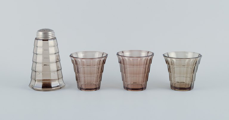 Simon Gate (1883-1945) for Orrefors/Sandvik, Sweden.A set of three drinking glasses and a sugar shaker in Art Deco style, in smoked coloured pressed glass.