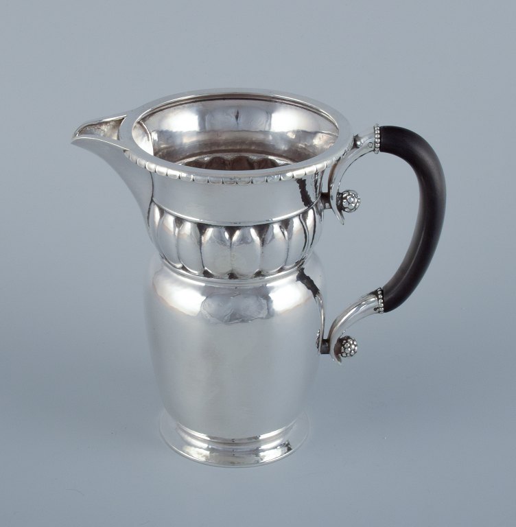 Georg Jensen, large Art Nouveau pitcher in sterling silver. Early and rare model. Hammered finish. Ebony handle.