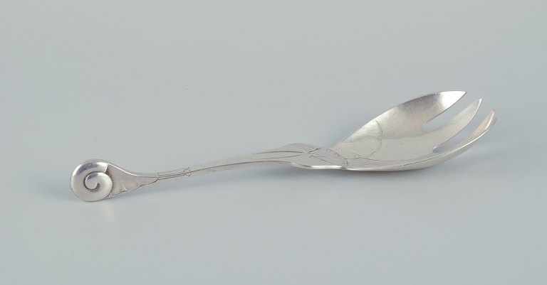 Early and rare Georg Jensen "Ornamental" pattern serving-fork chased with foliage and with a spiral shell finial. Sterling silver.