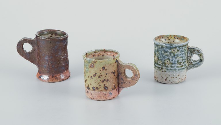 Danish studio ceramicist.Three unique miniature ceramic mugs.Decorated with various earth-toned glazes.