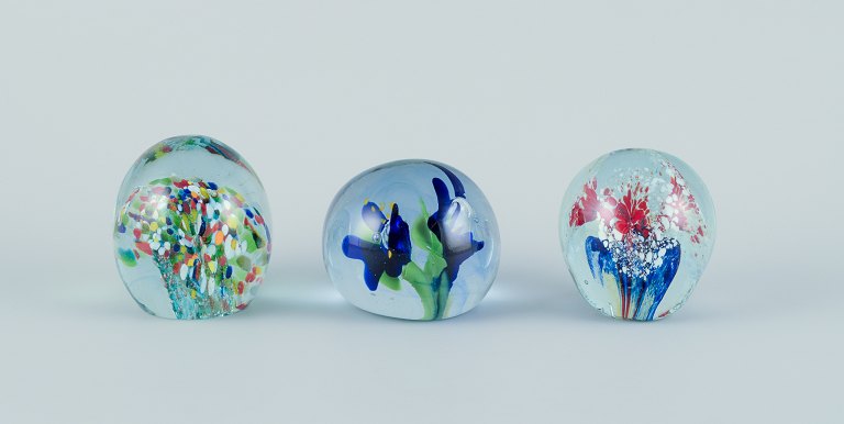 Scandinavian glass artist. Set of three paperweights in art glass. Flower motifs and more embedded in the glass. Handmade.