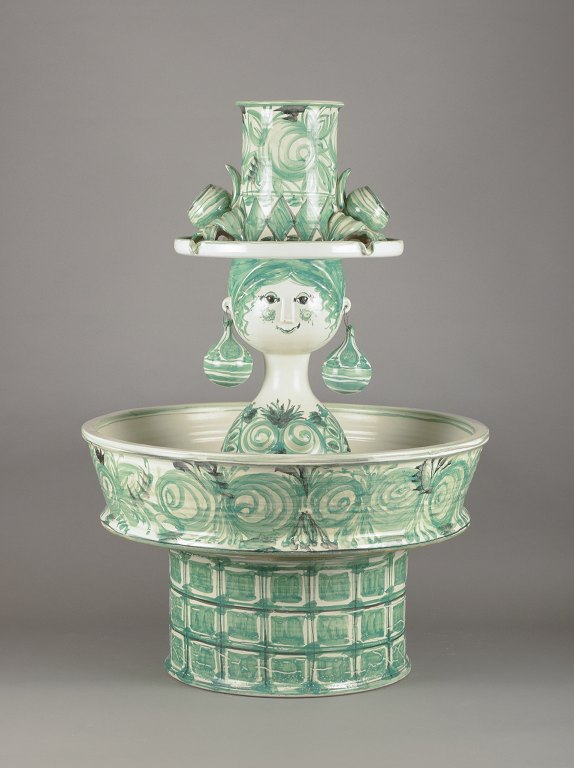 Bjørn Wiinblad (1918-2006), eget værksted. Kolossal fontæne, kvindeansigt med ørenringe og høj hat. Håndmalet i grønne nuancer.