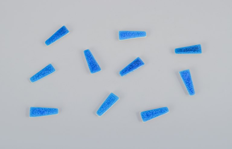 Ole Bjørn Krüger (1922-2007), dansk billedhugger og keramiker. Ti unika brocher i glaseret stentøj i blå nuancer.