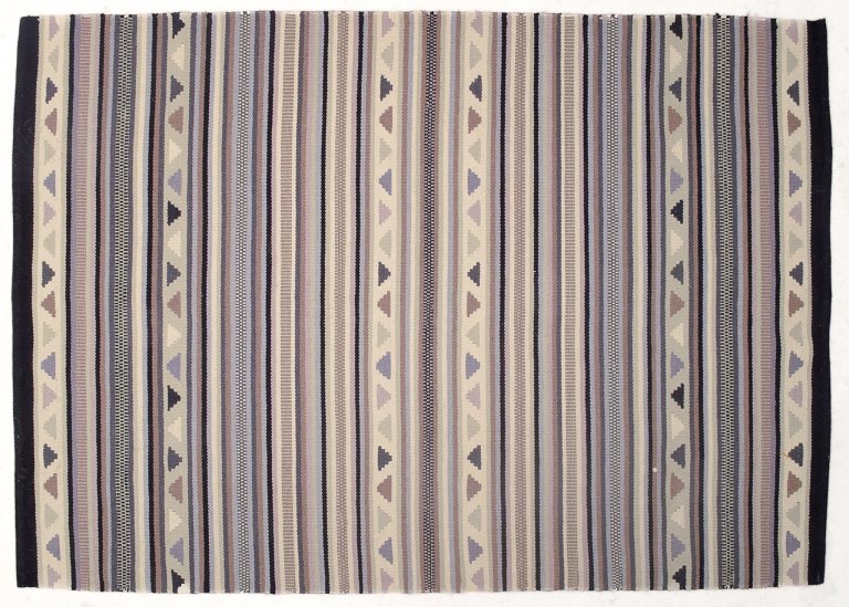 Svensk tekstildesigner.
Håndknyttet tæppe af uld. 
Vævet i flere farver.