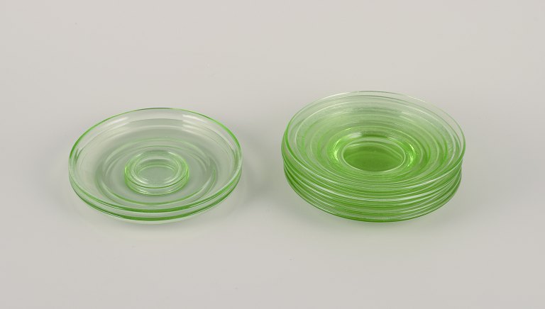 A set of seven green glass plates.
