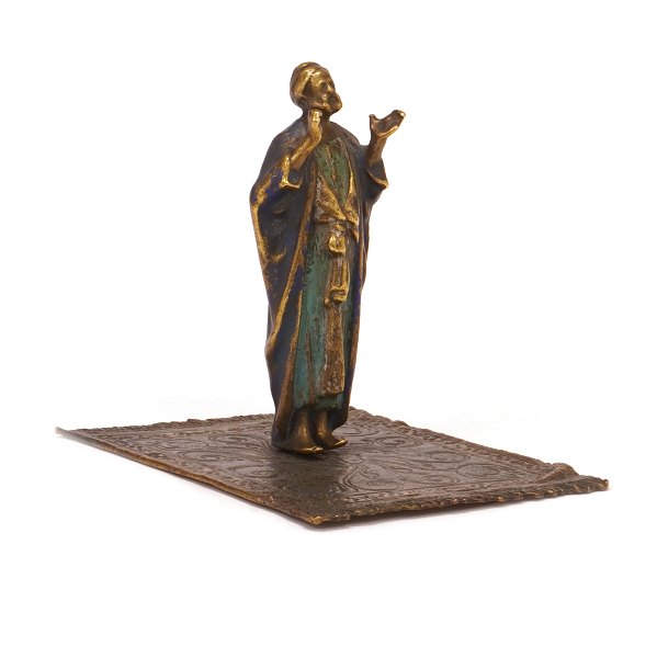 Figur forestillende orientalsk mand på tæppe i formessinget tin og dekoreret. H: 9,5cm. Base: 9x11cm