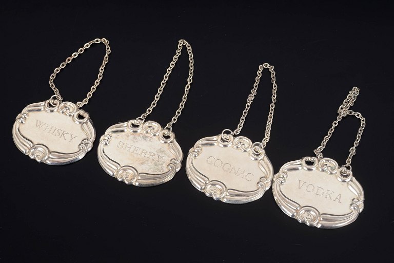 Four silver decanter labels.